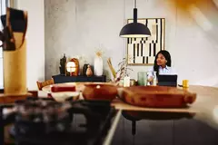 male looking serious, sitting at a kitchen table with tablet.
