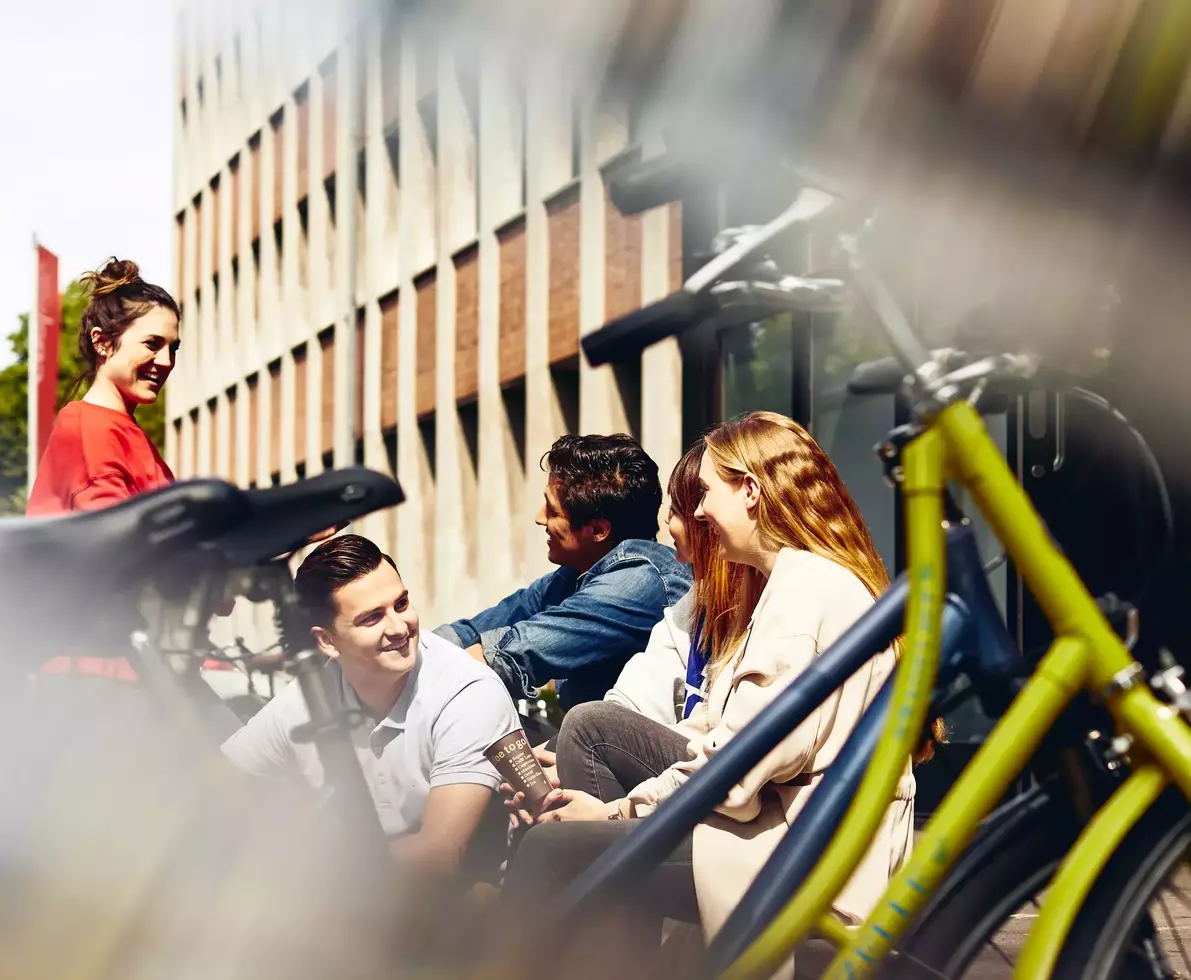 Group of students sitting outside next to bikes.
