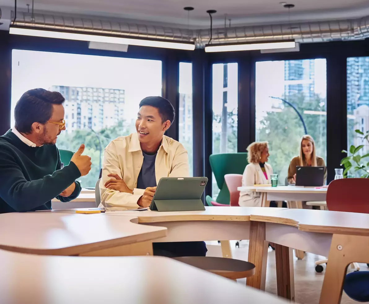 2 males having a discussion at a table with tablet in front of them